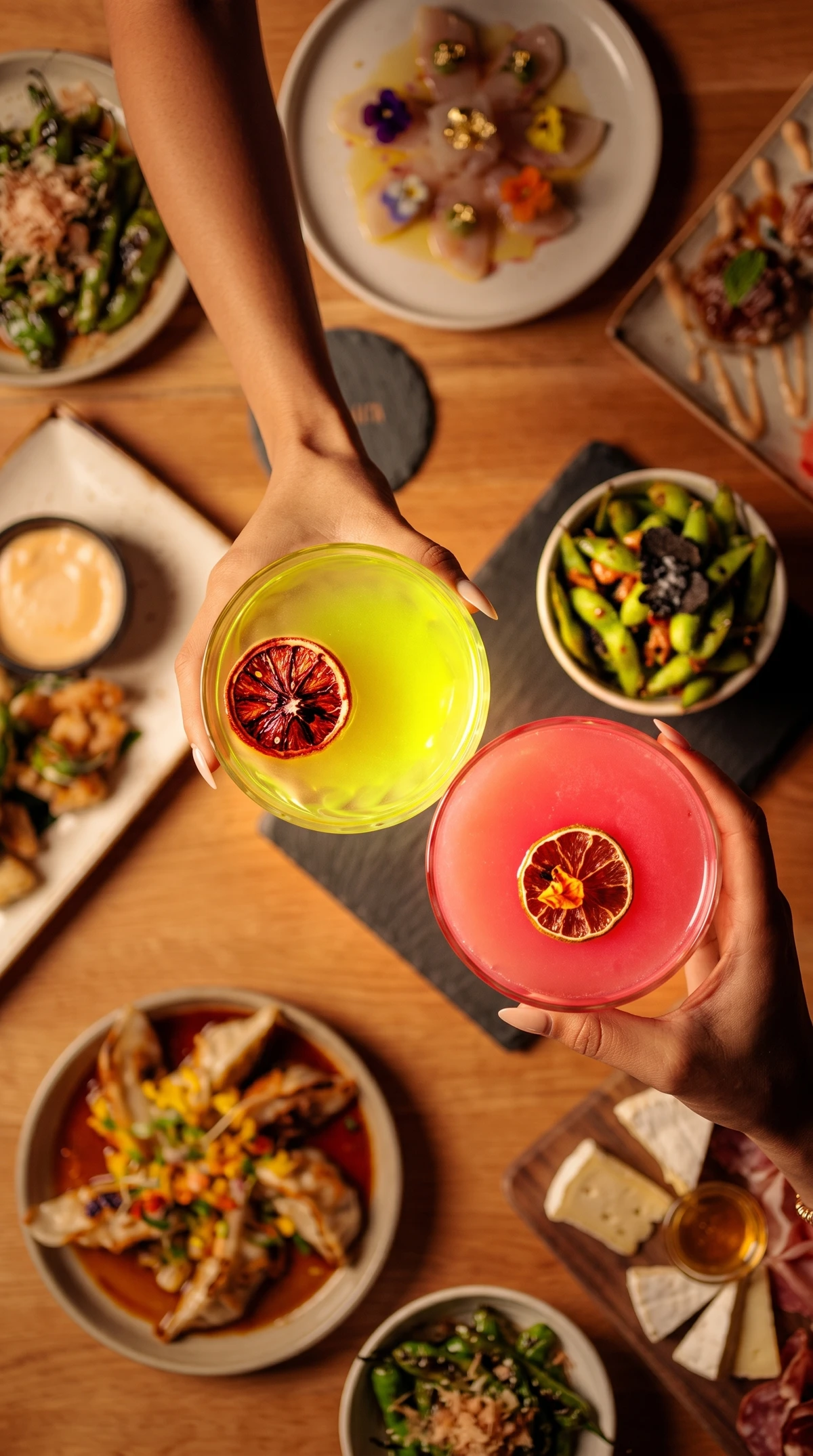 Two people toasting colorful cocktails