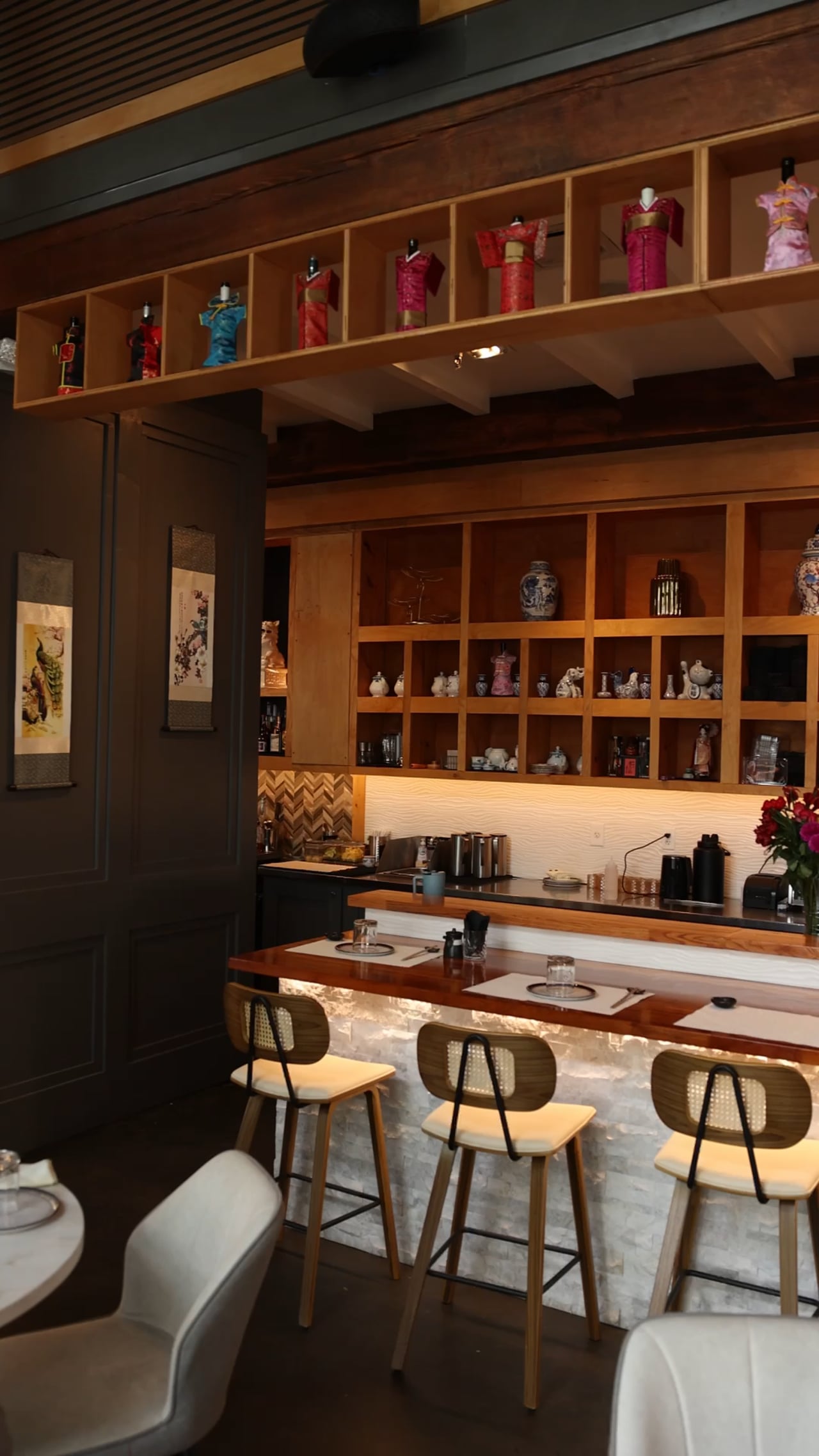 A sushi restaurant’s bar counter with rattan stools and wooden shelving